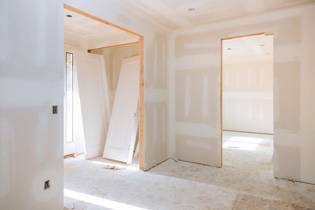 Interior drywall installation in a new home under construction, showing unfinished walls and door op.